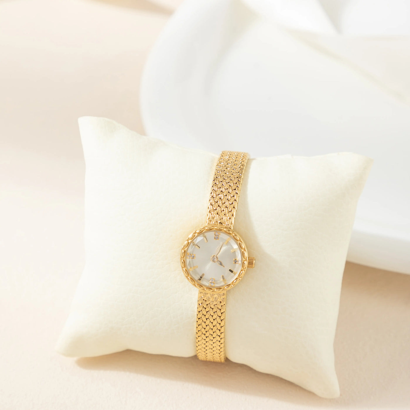 Reloj Malla Serena dorado presentado sobre un cojín claro