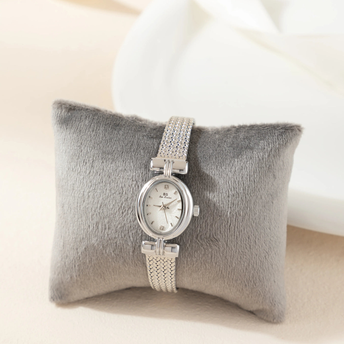 Reloj Ovalado Aurelia plateado presentado sobre un cojín gris