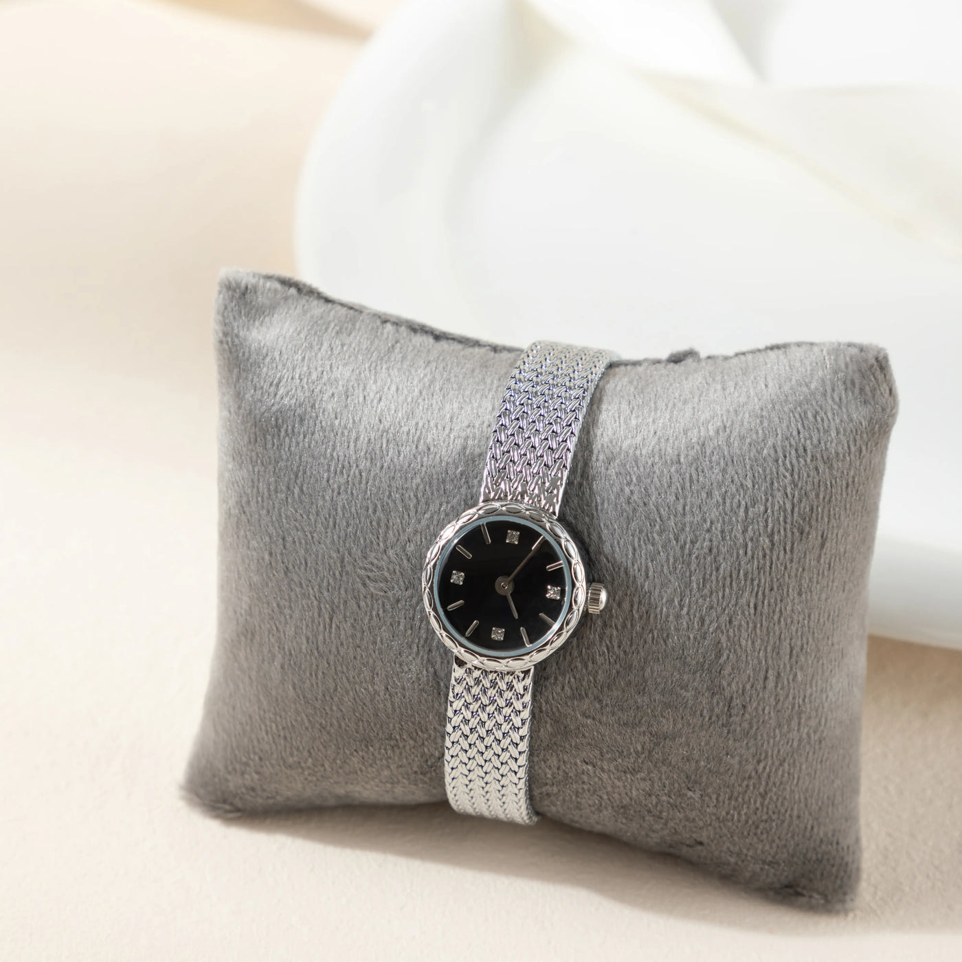 Reloj Malla Serena plateado con esfera negra sobre un cojín gris