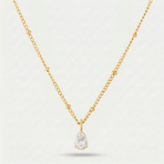 Collar Gota de Luz Amira dorado con piedra blanca sobre fondo claro