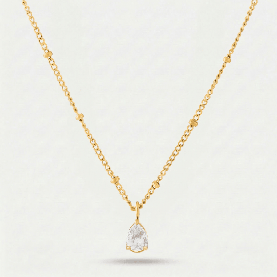 Collar Gota de Luz Amira dorado con piedra blanca sobre fondo claro