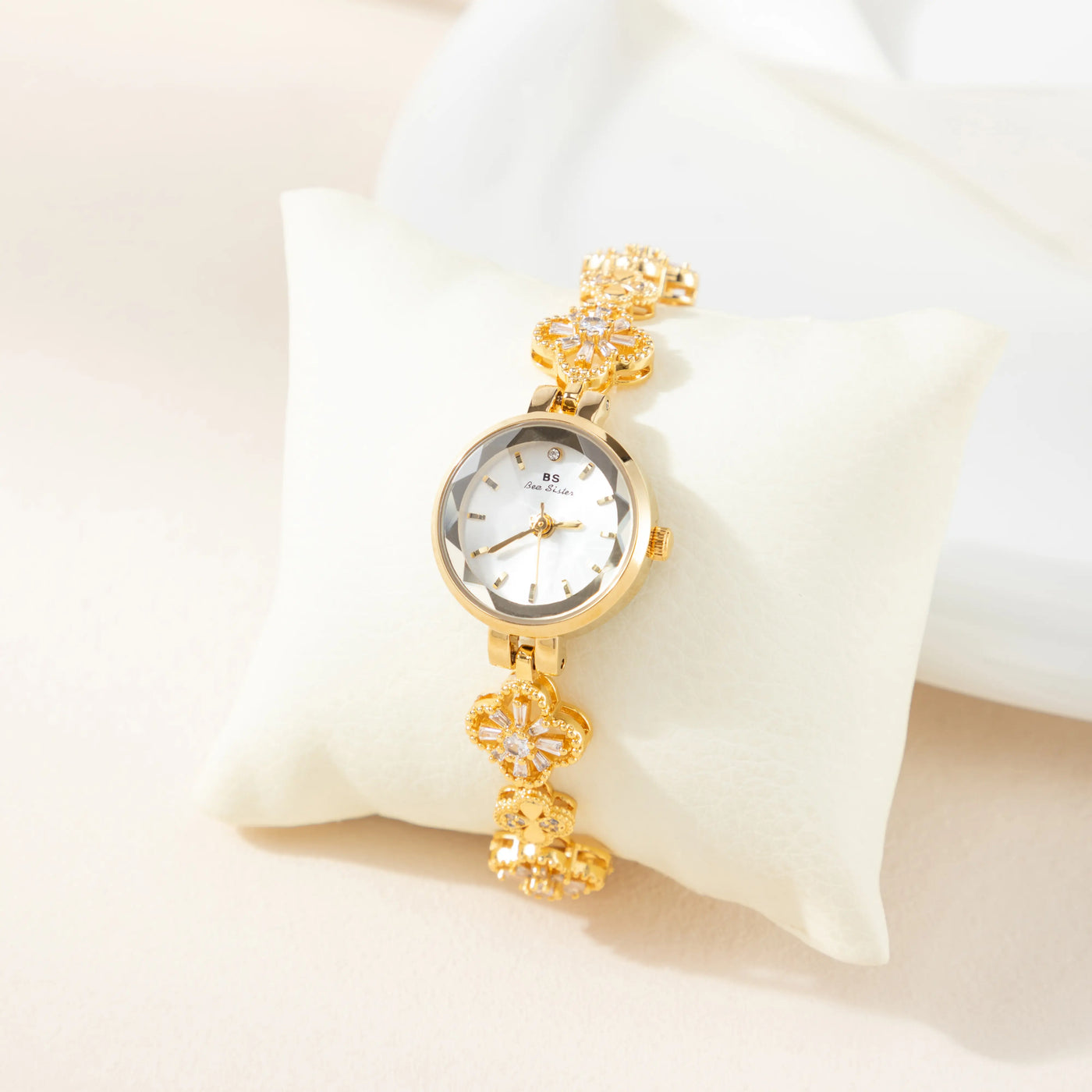 Reloj Floral Dalia dorado presentado sobre un cojín claro