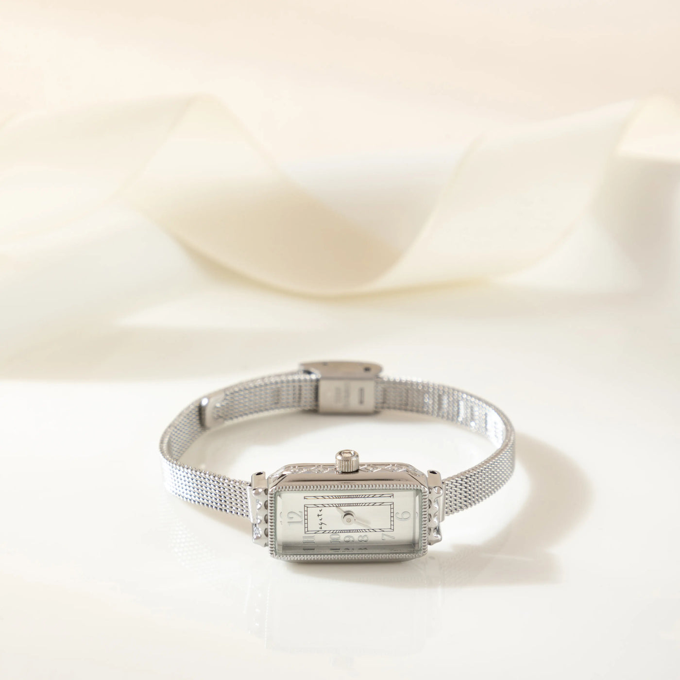 Reloj Rectangular Celeste plateado sobre una superficie de seda
