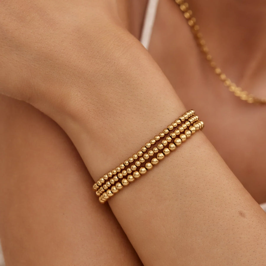 Detalle de la Pulsera Triple Esferas Oriana dorada en la muñeca