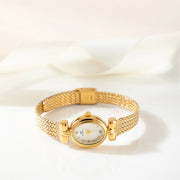 Reloj Ovalado Aurelia dorado sobre una superficie de color crema