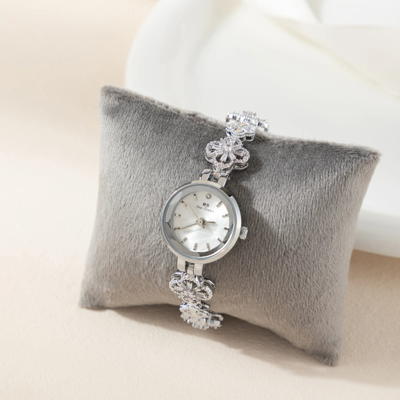 Reloj Floral Dalia plateado presentado sobre un cojín gris