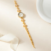 Reloj Floral Dalia dorado sobre una superficie de color crema
