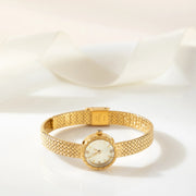 Reloj Malla Serena dorado sobre una superficie de color crema