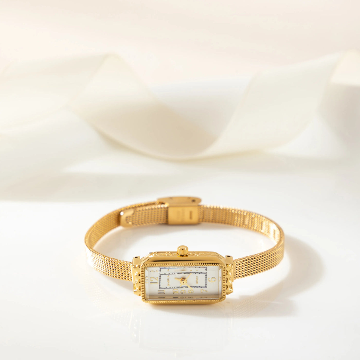 Reloj Rectangular Celeste dorado sobre una superficie de seda