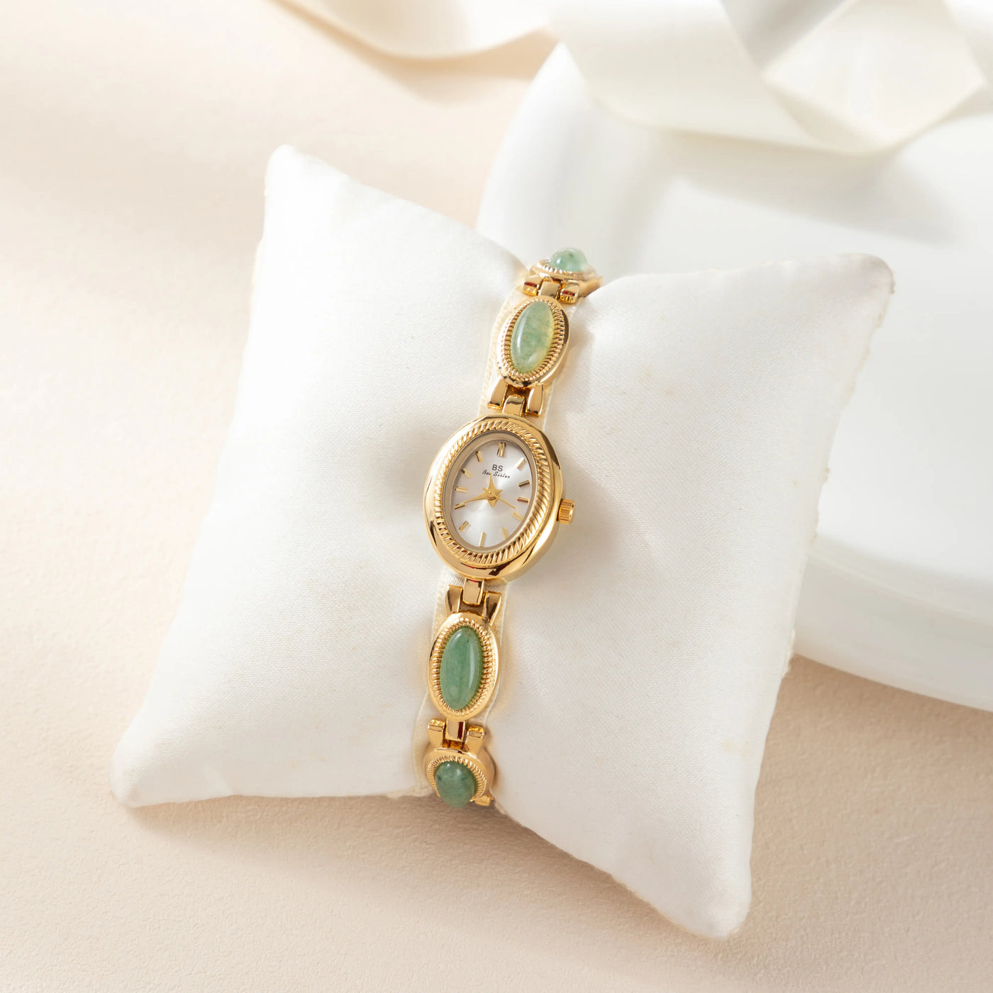 Reloj Rectangular Nerina dorado presentado sobre un cojín claro