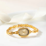 Reloj Ovalado Amara dorado sobre una superficie de color crema