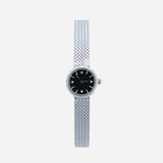 Reloj Malla Serena plateado con esfera negra sobre fondo claro