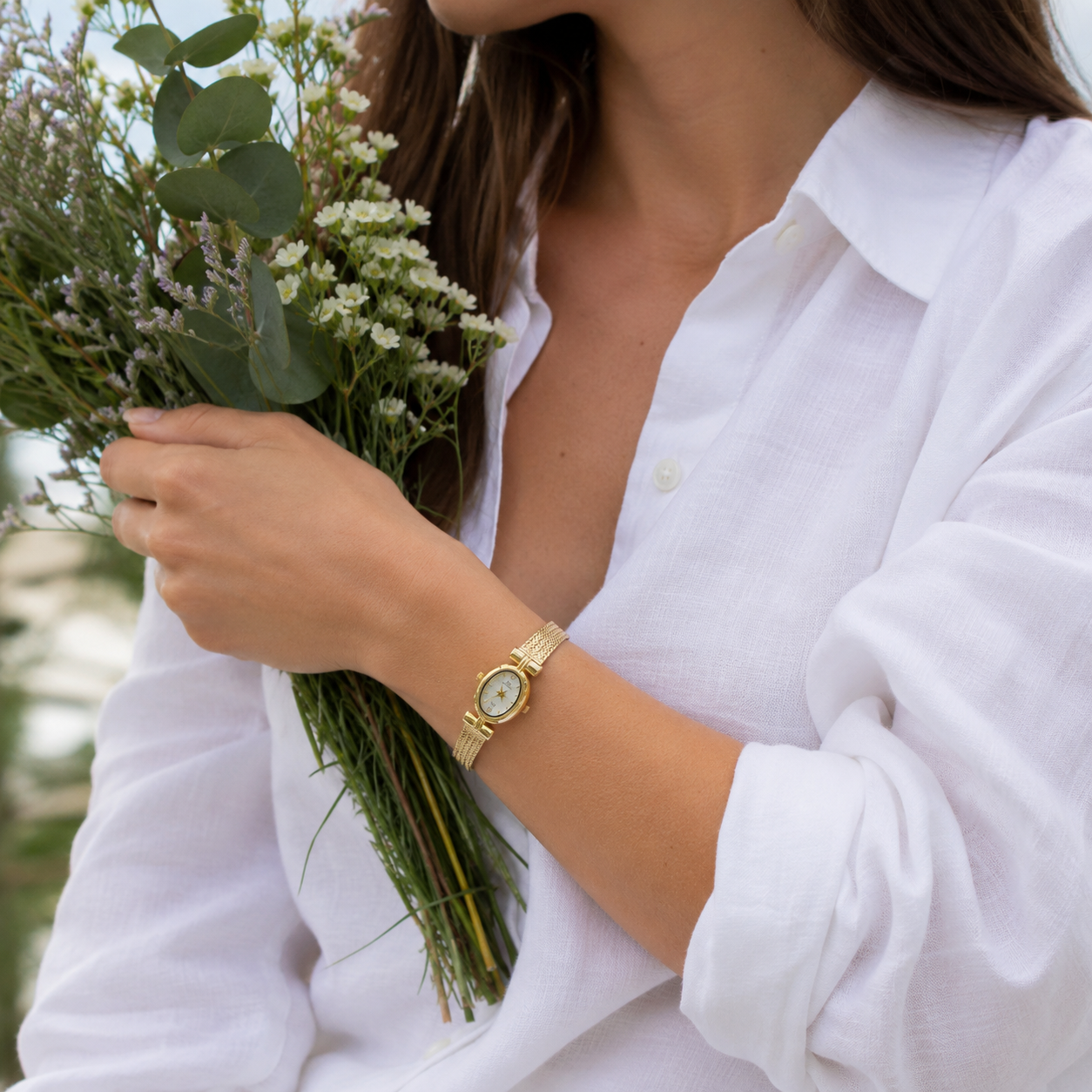 Mujer llevando el Reloj Ovalado Aurelia dorado en la muñeca