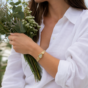Mujer llevando el Reloj Ovalado Aurelia dorado en la muñeca