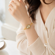 Mujer llevando el Reloj Ovalado Amara dorado en la muñeca