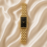 Reloj Rectangular Liora con esfera negra presentado sobre un cojín claro