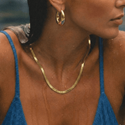 Mujer con top azul llevando el Collar Cadena Plana Aitana dorado