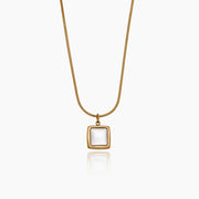 Collar Perla Enmarcada Alina dorado con perla blanca sobre fondo claro