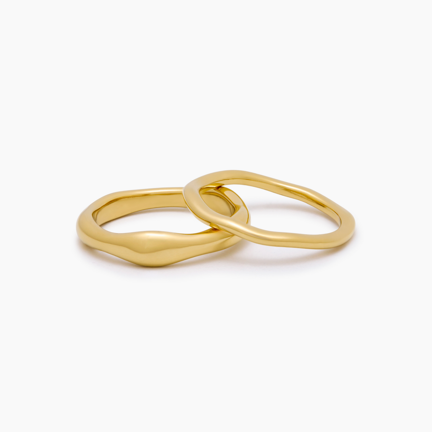Dúo de Anillos Ondulados Naia dorados sobre fondo blanco con un reflejo suave