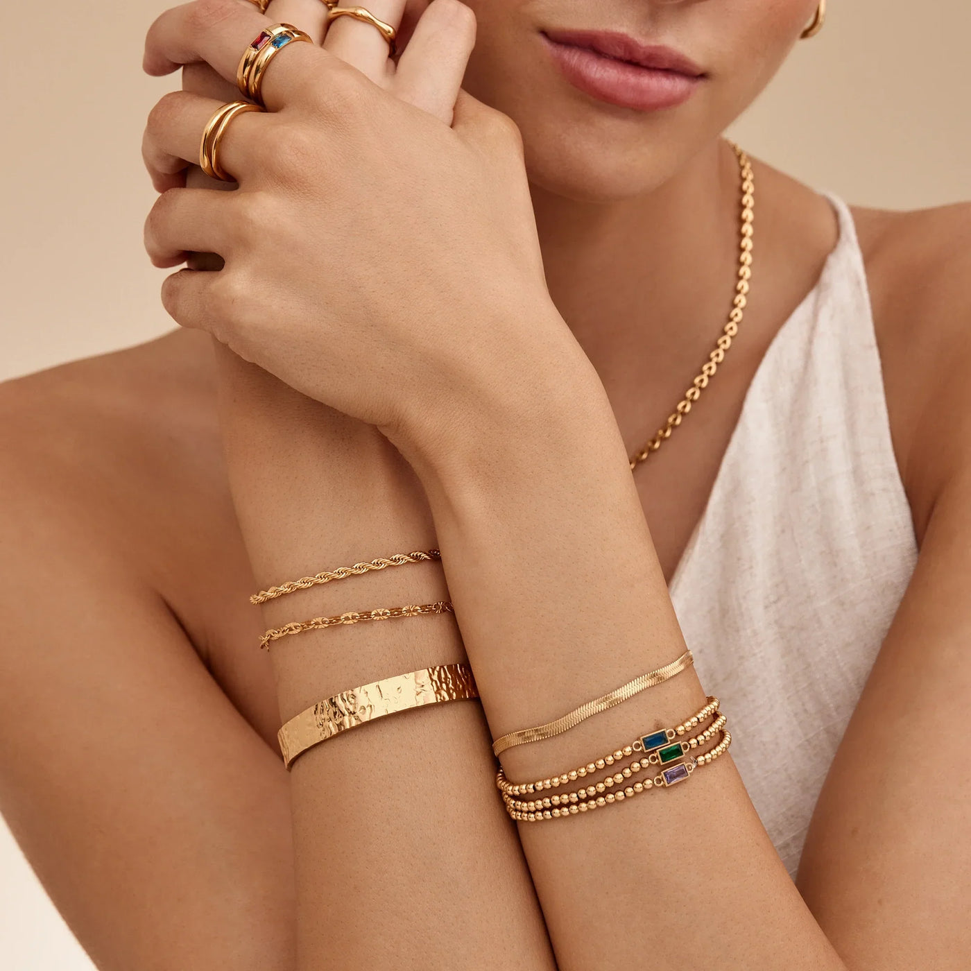 Mujer combinando la Pulsera Cadena Destellos Naia con otras pulseras doradas