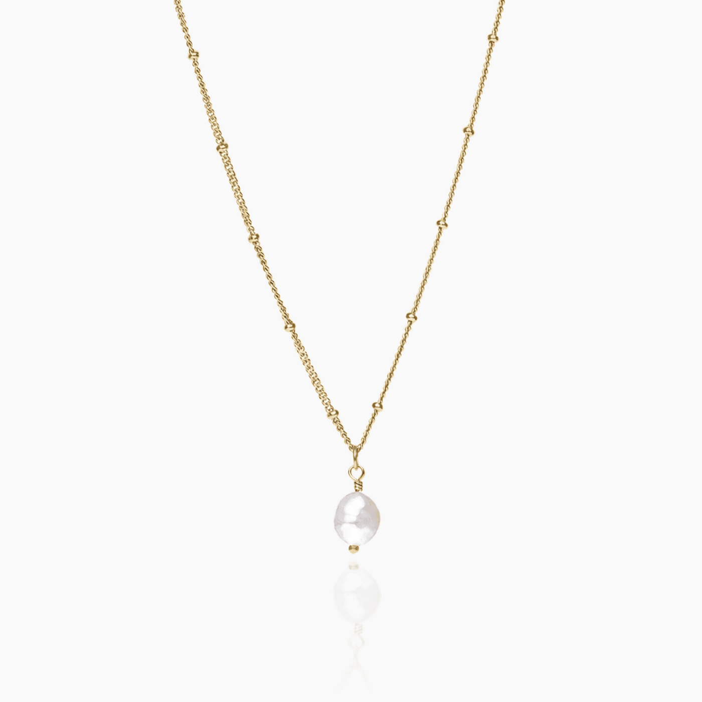 Collar dorado con perla barroca sobre fondo blanco