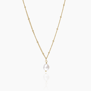 Collar dorado con perla barroca sobre fondo blanco