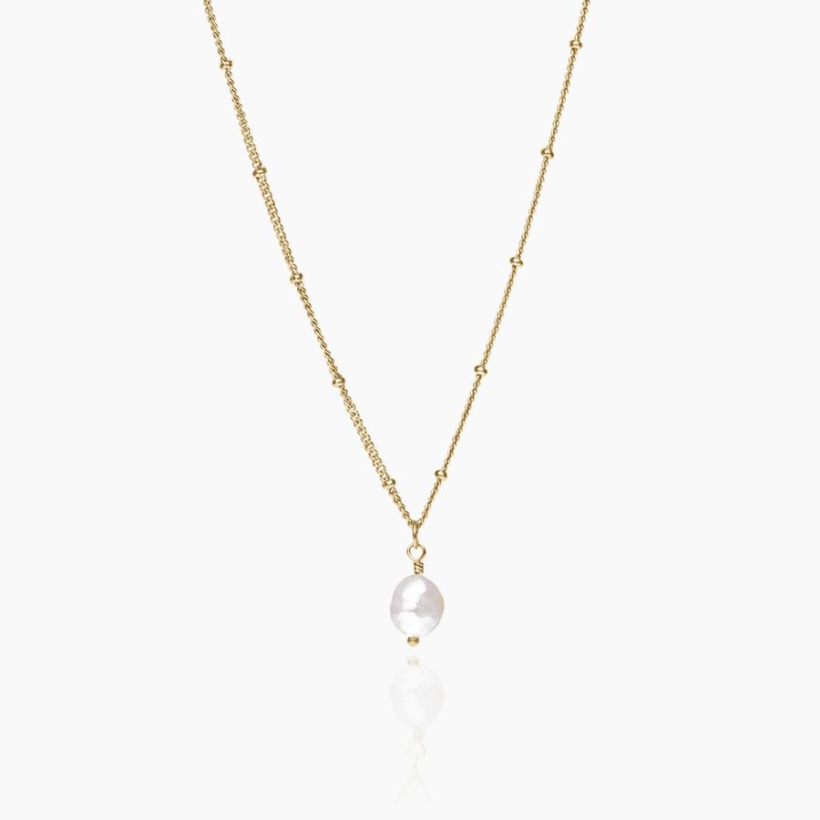 Collar dorado con perla barroca sobre fondo blanco