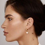 Mujer llevando los Pendientes Huggie Corazón Eliana dorados