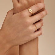 Anillo Doble Enlace Elia dorado lucido en la mano junto a otros anillos