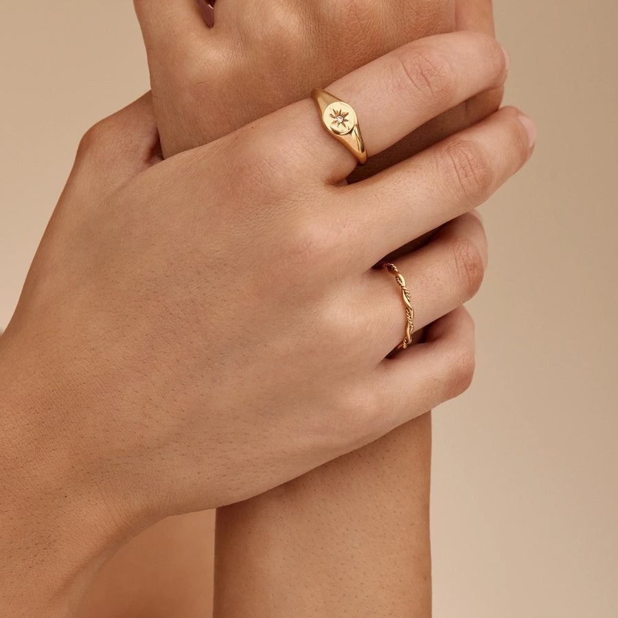 Anillo Doble Enlace Elia dorado lucido en la mano junto a otros anillos