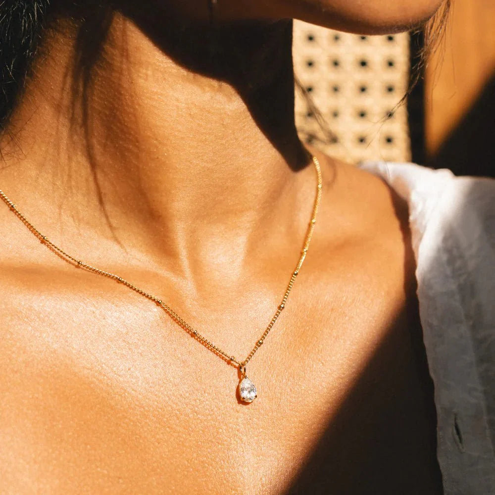 Primer plano del Collar Gota de Luz Amira dorado en el cuello