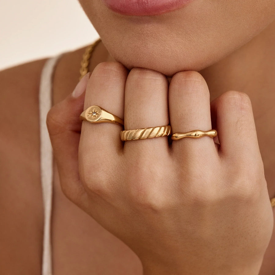 Anillo Ondulado Nerea dorado lucido en la mano junto a otros anillos